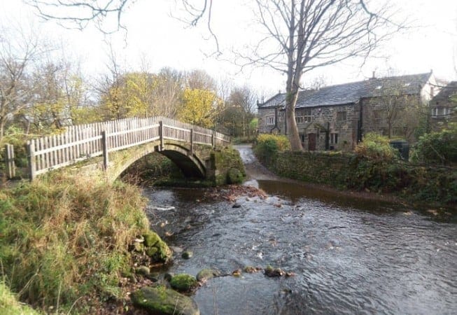 View of Beckfoot Farm and Beckfoot packhorse bridge above the Harden Beck in Bingley